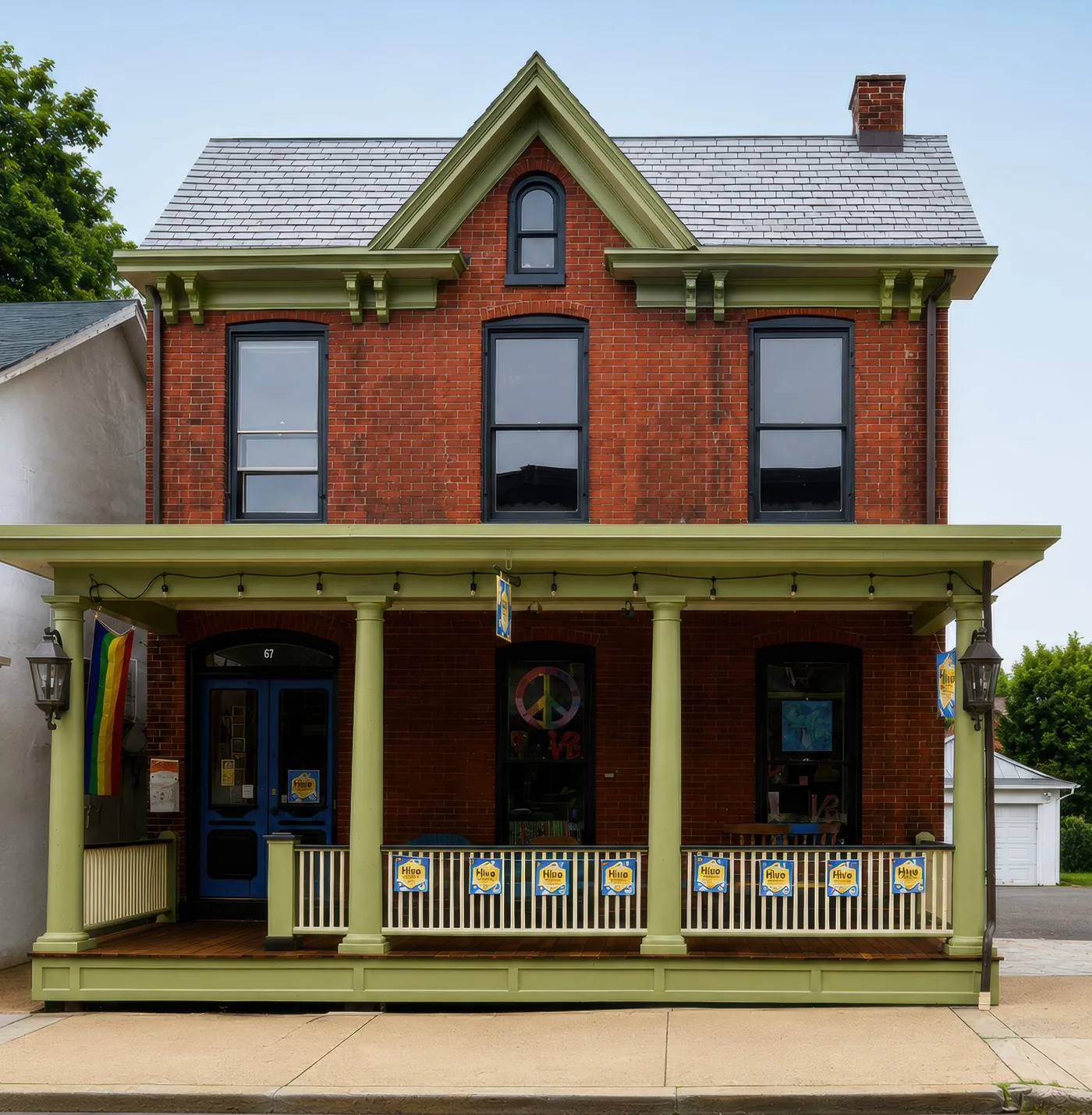 The red brick house at 67 Bridge Street, with a sage-green porch, blue double doors and arched windows